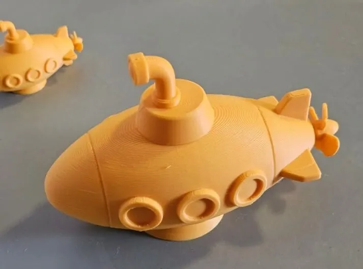 Dois submarinos amarelos impressos em 3D sobre uma mesa cinza
